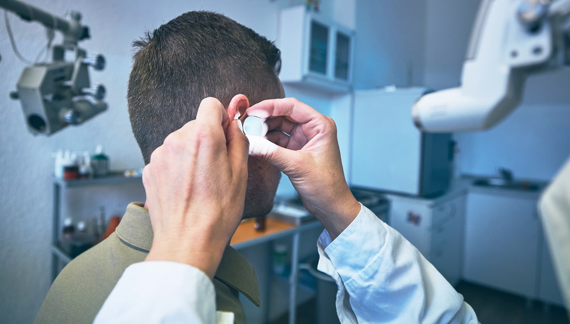Audiologist fitting an earplug during a hearing test